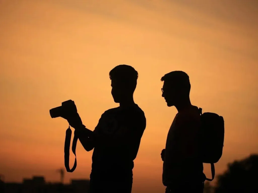 Silhueta de dois fotógrafos discutindo técnicas ao pôr do sol - Curso de Fotografia Online Jornada Viver de Fotografia por Adriano Portugal